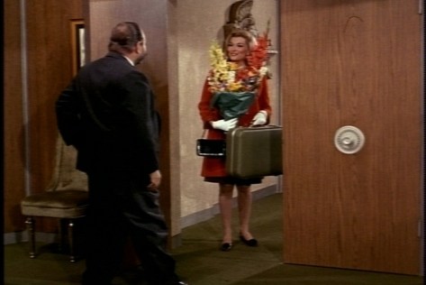 Her flower arrangement is garish, but I love her whole ensemble: the coat, the gloves, the purse and the dress underneath.